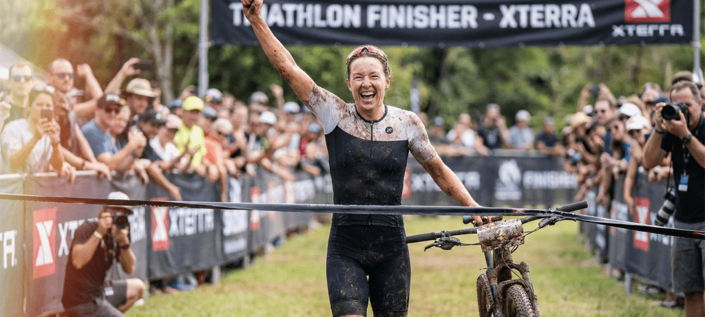 une athlète féminine sur la ligne d'arrivée d'un triathlon avec son vtt
